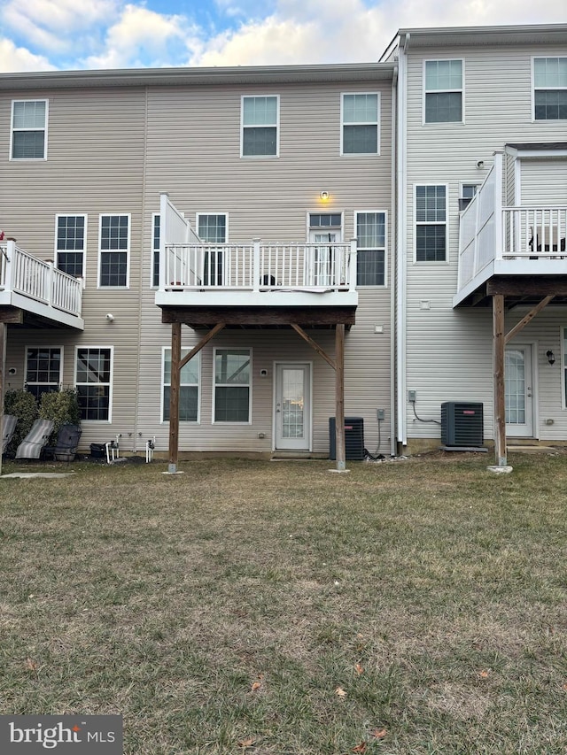 rear view of house with cooling unit and a yard