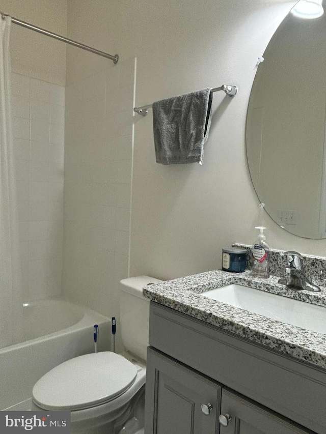 full bathroom featuring tiled shower / bath, vanity, and toilet