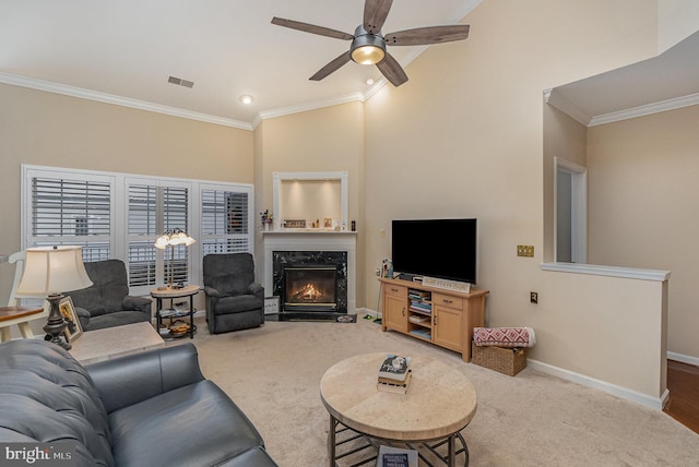 carpeted living room with ceiling fan, a high end fireplace, a high ceiling, and ornamental molding