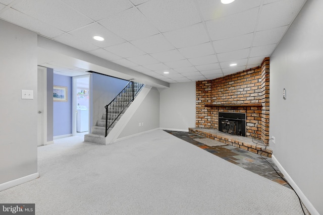 carpeted living room with a brick fireplace and a drop ceiling