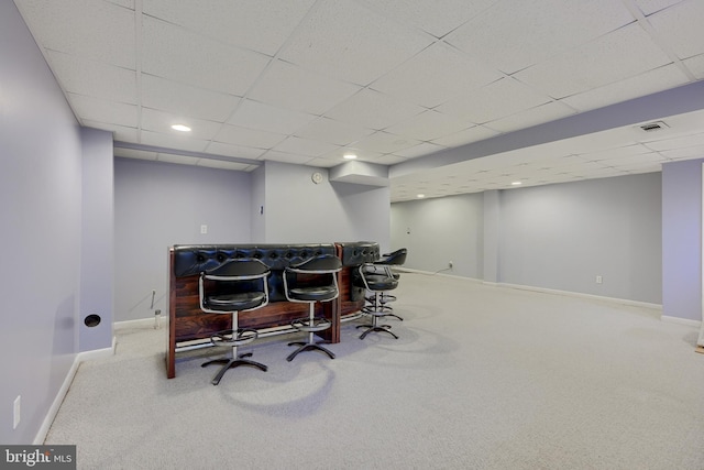 carpeted office space featuring a paneled ceiling and bar area