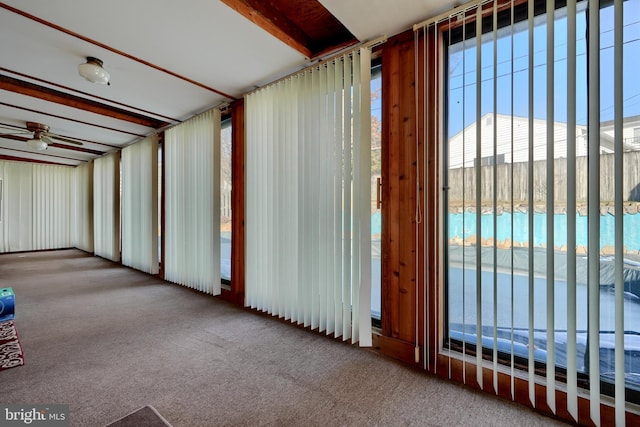 carpeted spare room with ceiling fan and beam ceiling