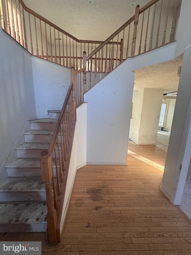 stairway featuring hardwood / wood-style floors and a textured ceiling