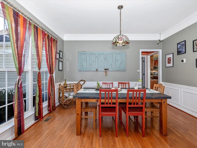 dining area featuring ornamental molding and light hardwood / wood-style flooring