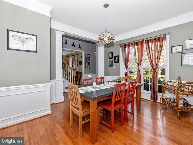 dining space with crown molding, wood-type flooring, and ornate columns