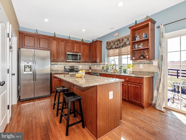 kitchen featuring sink, tasteful backsplash, a center island, light hardwood / wood-style flooring, and stainless steel appliances