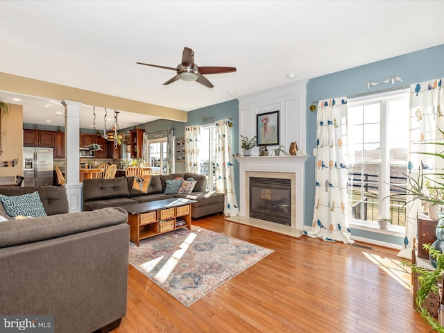 living room featuring ceiling fan, light hardwood / wood-style flooring, and ornate columns