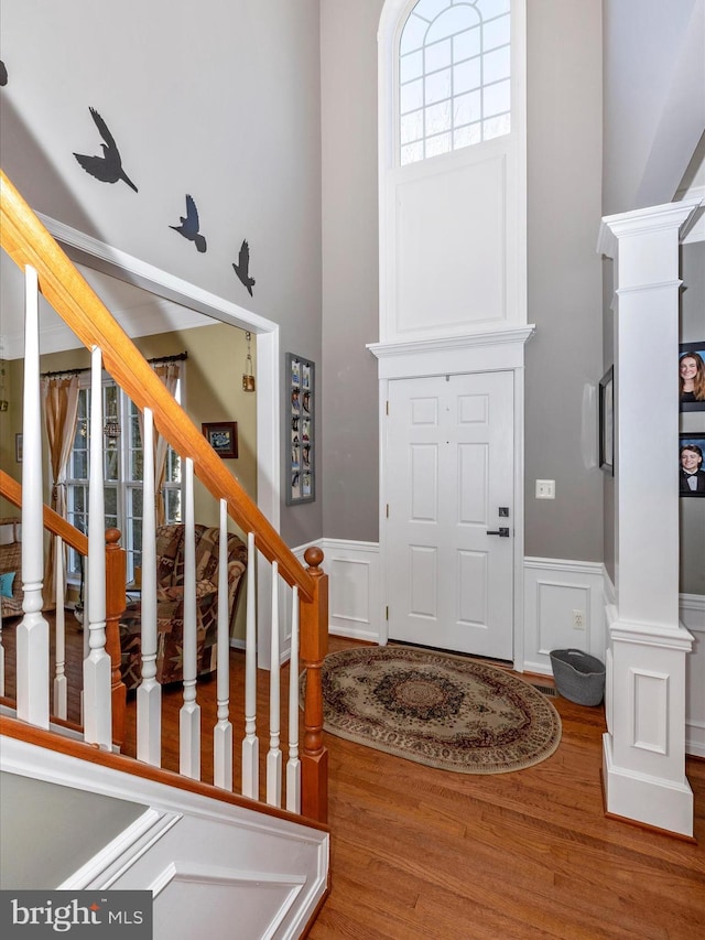 foyer entrance with wood-type flooring and decorative columns