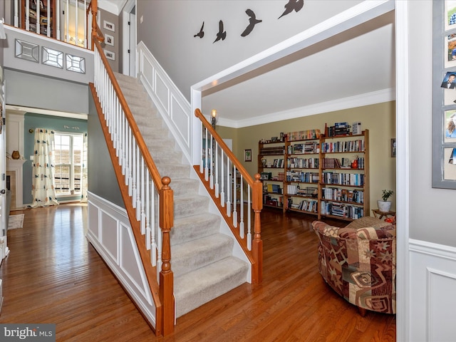 stairs with wood-type flooring and ornamental molding