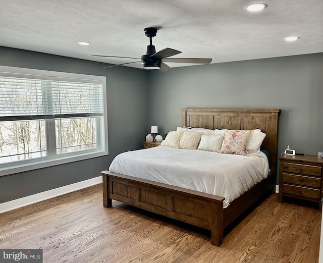 bedroom featuring hardwood / wood-style flooring, a textured ceiling, and ceiling fan