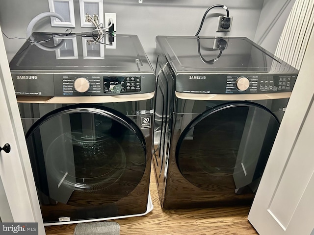 clothes washing area with hardwood / wood-style flooring and washer and dryer