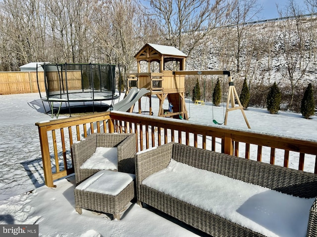 snow covered deck featuring a playground and a trampoline