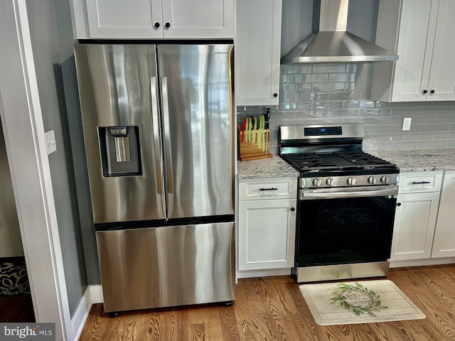 kitchen featuring tasteful backsplash, white cabinetry, appliances with stainless steel finishes, and wall chimney range hood