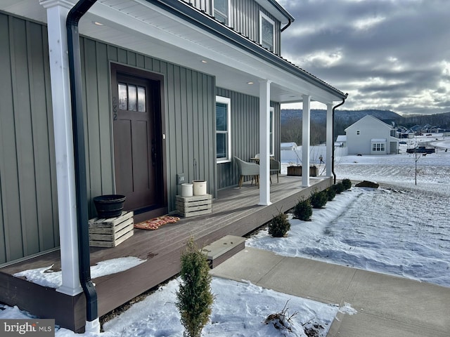 snow covered property entrance featuring a porch