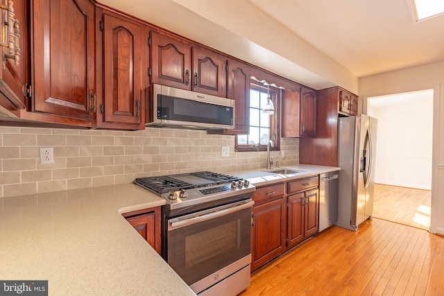 kitchen featuring appliances with stainless steel finishes, light hardwood / wood-style floors, backsplash, and sink