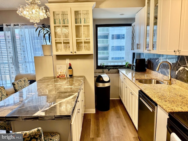 kitchen with decorative light fixtures, dishwasher, sink, light stone countertops, and white cabinets