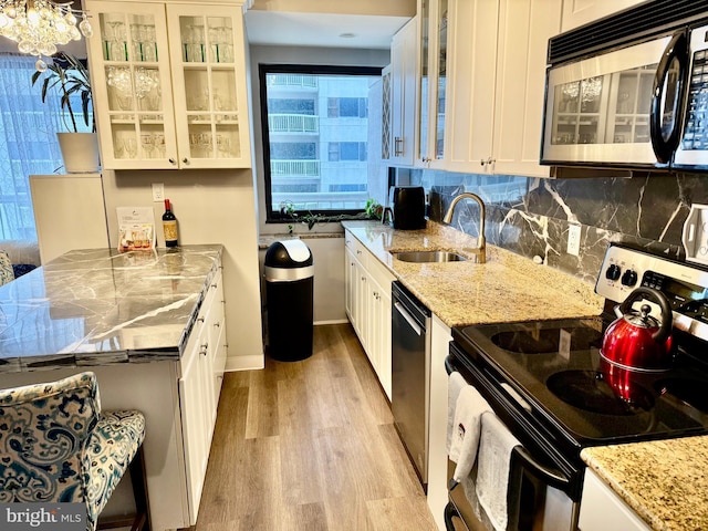 kitchen featuring white cabinets, sink, light stone counters, and stainless steel appliances