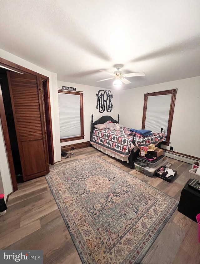 bedroom with hardwood / wood-style floors, ceiling fan, and a baseboard radiator