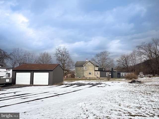 snowy yard with a garage and an outdoor structure