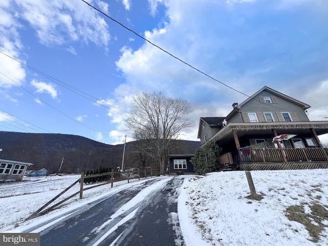 view of snow covered exterior with a mountain view and covered porch