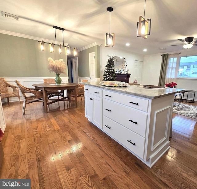 kitchen featuring a center island, pendant lighting, light stone counters, hardwood / wood-style flooring, and white cabinetry