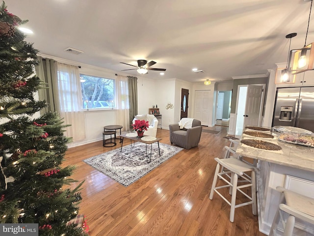 living room with light hardwood / wood-style floors, ceiling fan, and crown molding