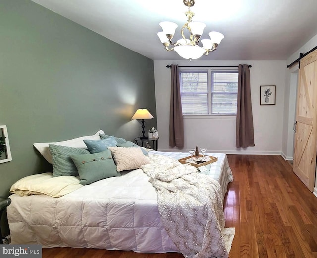 bedroom with wood-type flooring, a notable chandelier, and a barn door