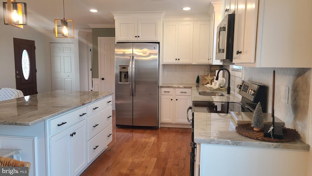 kitchen with stainless steel appliances, hanging light fixtures, light stone countertops, a kitchen island, and white cabinets