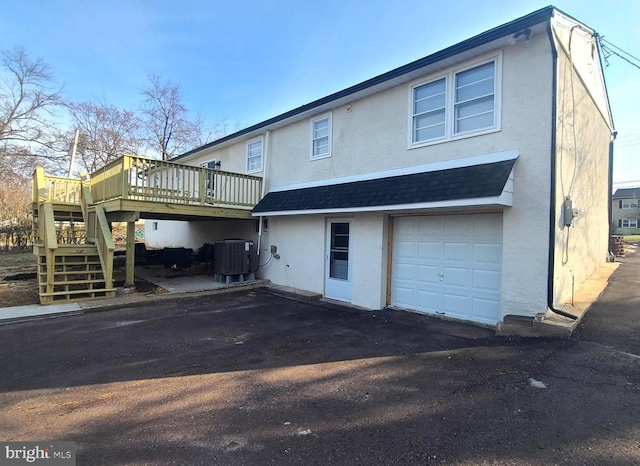 rear view of property with central air condition unit, a deck, and a garage