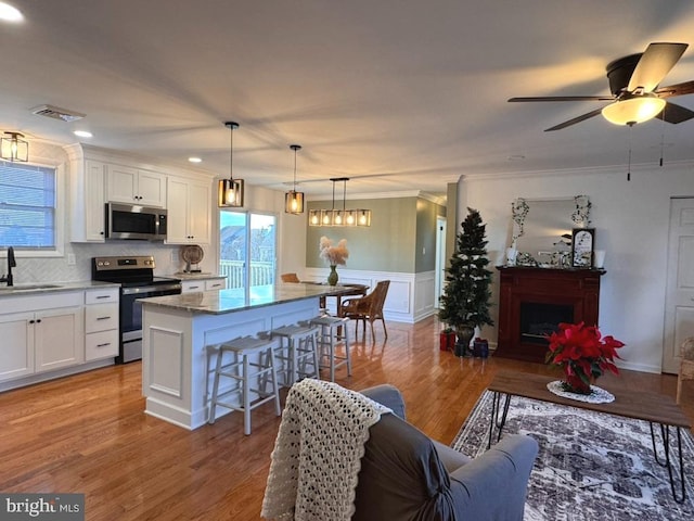 kitchen with pendant lighting, a center island, stainless steel appliances, a breakfast bar area, and white cabinetry