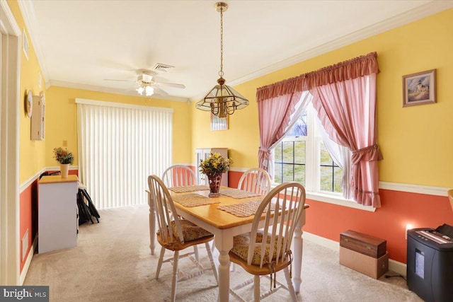 carpeted dining space featuring ceiling fan with notable chandelier and crown molding