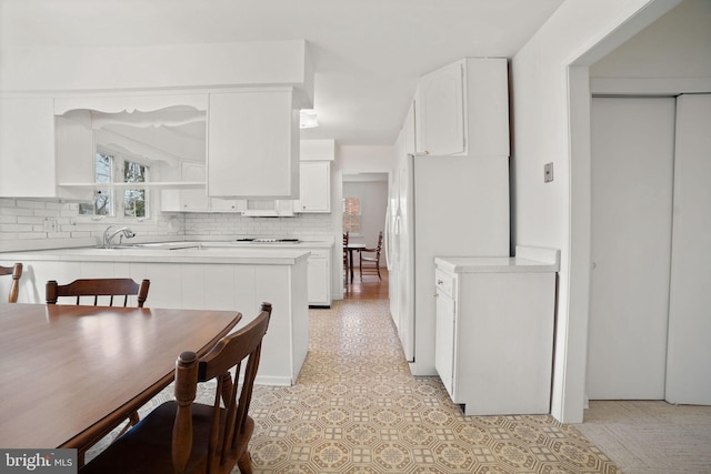 kitchen with white cabinets, backsplash, and white fridge