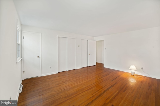 unfurnished bedroom with multiple closets and wood-type flooring