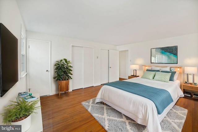 bedroom featuring two closets and dark hardwood / wood-style floors