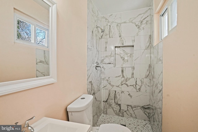 bathroom featuring toilet, a tile shower, and sink