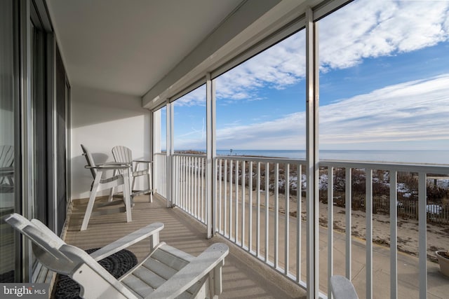 sunroom with a water view and a beach view