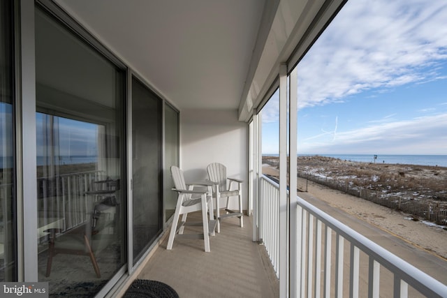 balcony with a water view and a view of the beach