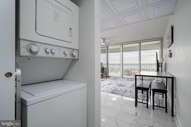 laundry area featuring ceiling fan and stacked washer / dryer