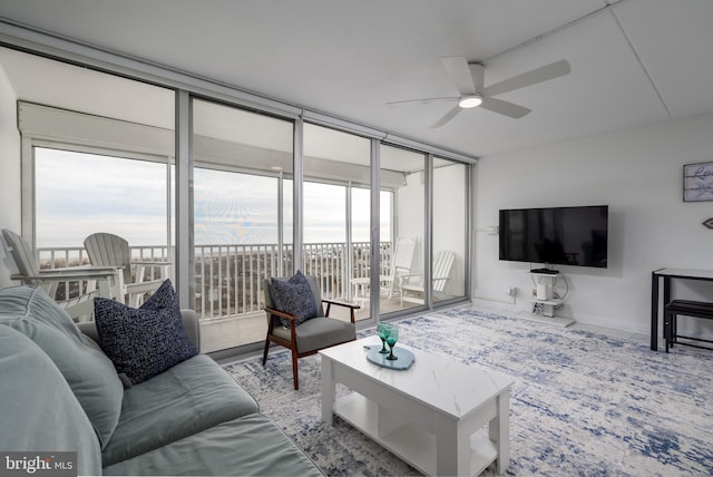 living room featuring ceiling fan and expansive windows