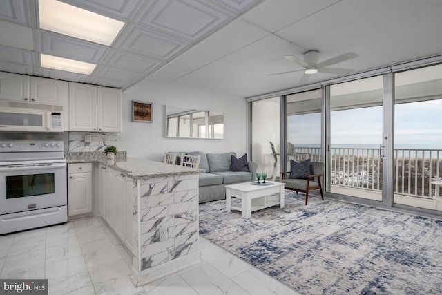 interior space with white cabinetry, kitchen peninsula, ceiling fan, white appliances, and a water view