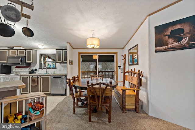 carpeted dining space with a textured ceiling, plenty of natural light, crown molding, and sink