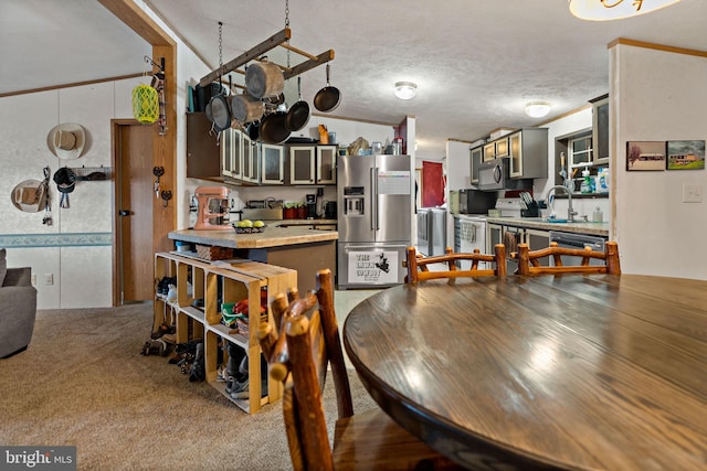 dining area with carpet, sink, crown molding, vaulted ceiling, and a textured ceiling