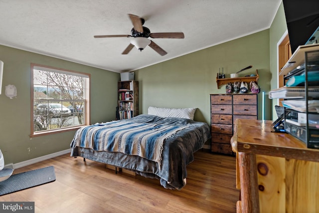 bedroom featuring ceiling fan, light hardwood / wood-style flooring, crown molding, and a textured ceiling