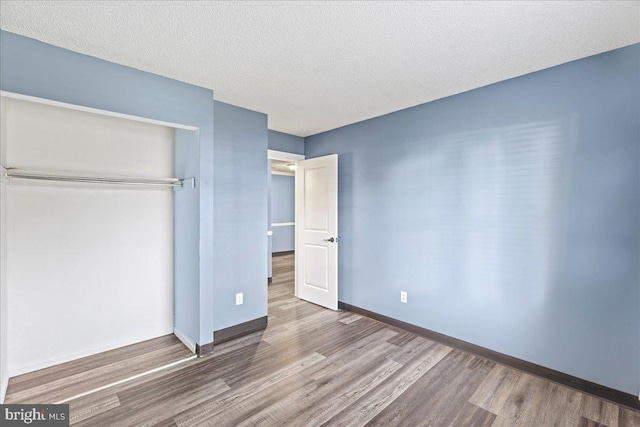 unfurnished bedroom with a textured ceiling, a closet, and hardwood / wood-style floors