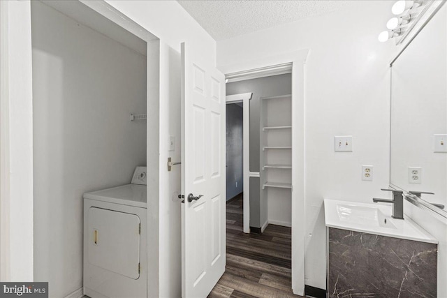 bathroom with a textured ceiling, washer / clothes dryer, vanity, and wood-type flooring