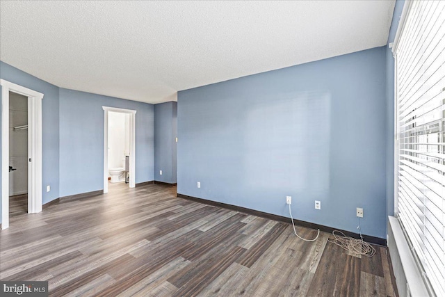 empty room with dark wood-type flooring and a textured ceiling