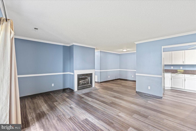 unfurnished living room with wood-type flooring, a textured ceiling, and crown molding