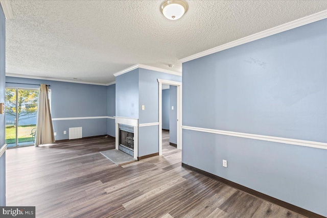 empty room with a textured ceiling, ornamental molding, and dark hardwood / wood-style flooring