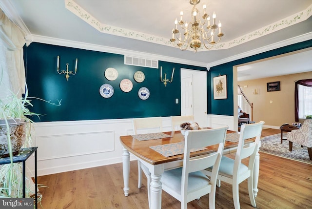 dining room featuring an inviting chandelier, crown molding, hardwood / wood-style flooring, and a tray ceiling