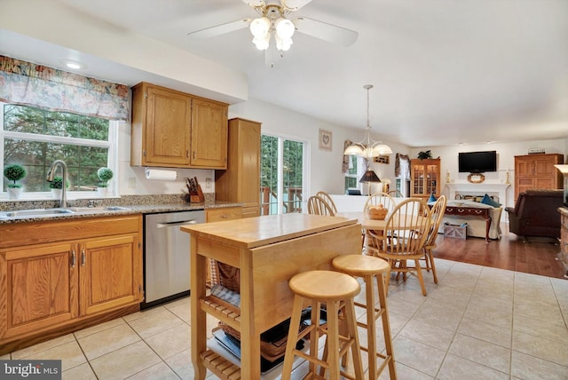 kitchen with ceiling fan with notable chandelier, pendant lighting, dishwasher, sink, and light tile patterned floors